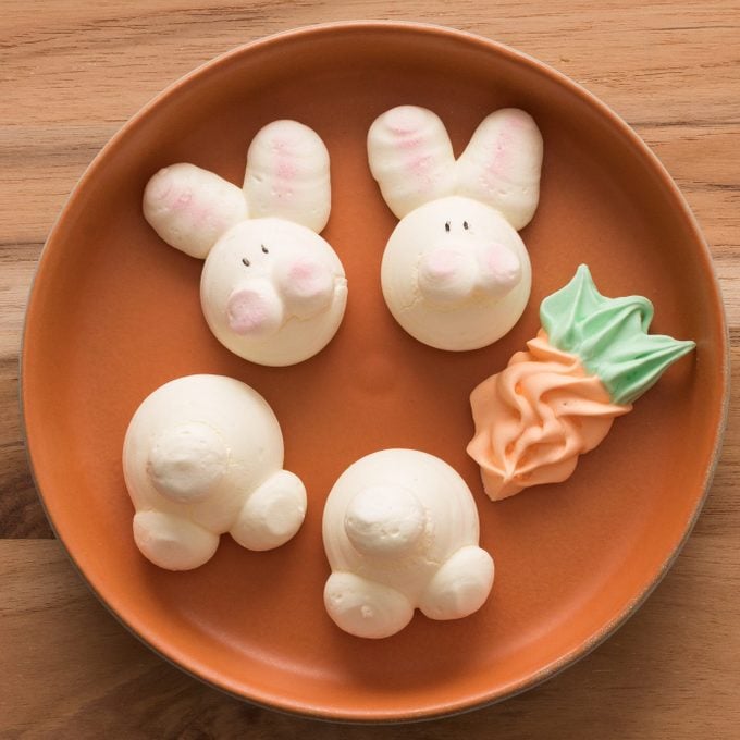 Cute Easter Bunny and carrot Meringues on wooden background