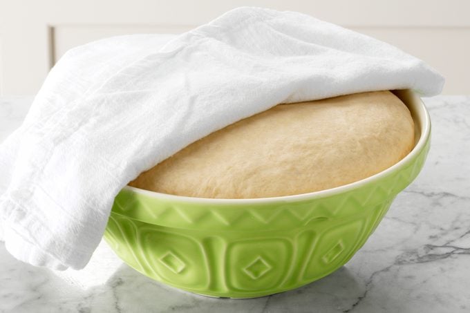 proofing bread dough in a bowl with towel covering the bowl